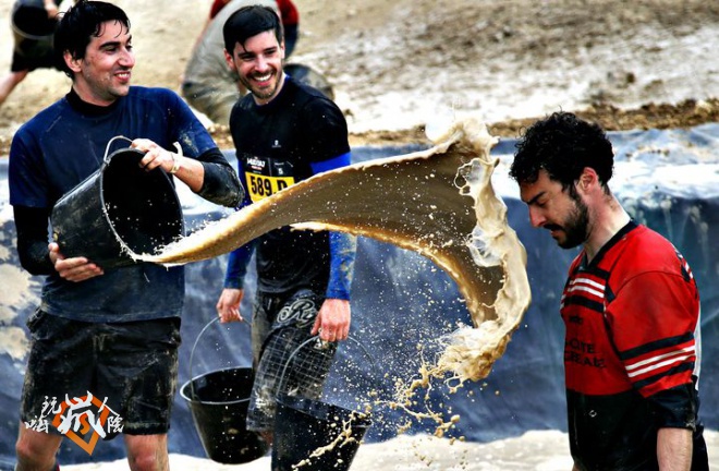 A participant in the Mud Day event throws a bucket of mud at a f