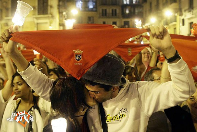 Revellers kiss as they hold candles and red scarves during the closing ceremony of San Fermin festival in Pamplona
