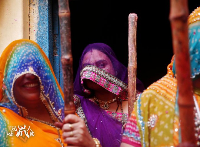 Veiled women wait to beat men with sticks during Lathmar Holi at Barsana